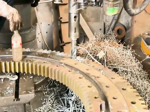 A machining tool and metal chips around a large steel gear.